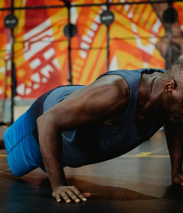 Focused man performing a bodyweight strength exercise in a minimalist dark environment.